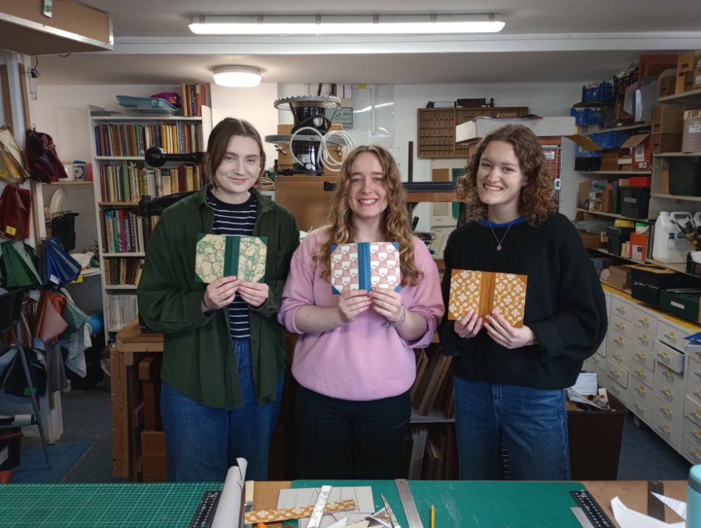 Three women holding books they made on the introductory course